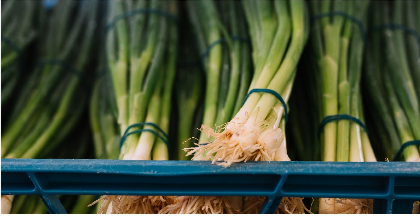 Bundles of fresh green garlic in a market crate